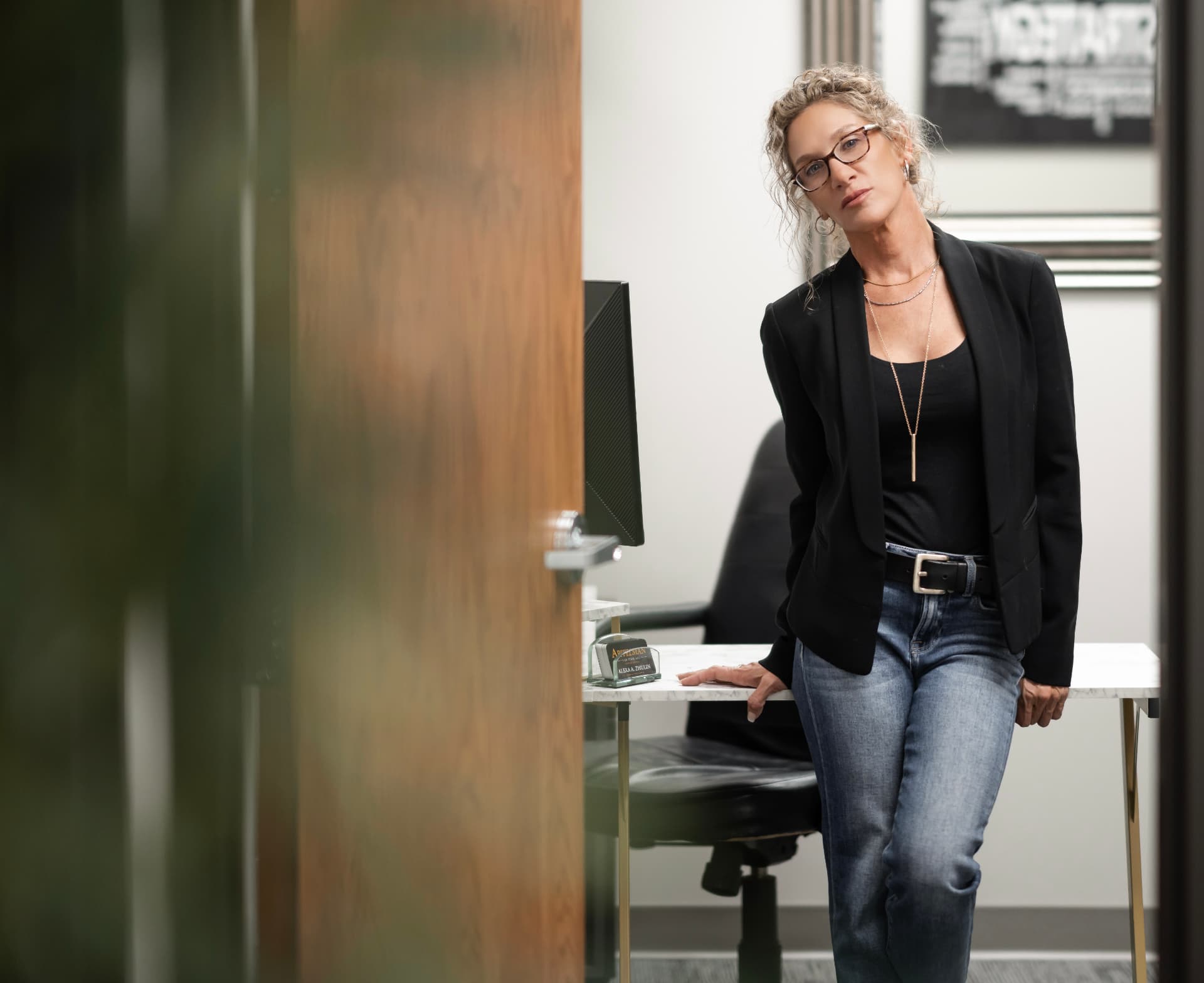 Joie Schubert in her office, wearing a black blazer and her signature glasses